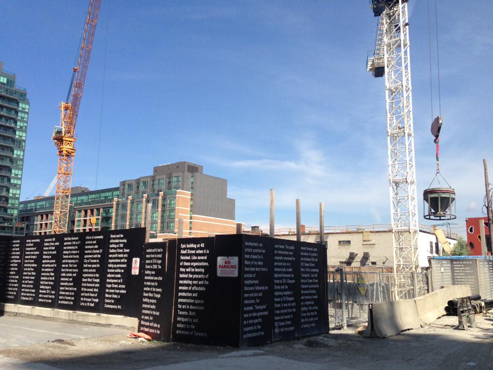 A view of Corwyn Lund's text work <em>Word Count</em> on the hoarding of the condo construction site where 48 Abell once stood. The artwork recounts Lund's difficult experiences finding live/work spaces in Toronto and his reflections on changes in the Queen West area.