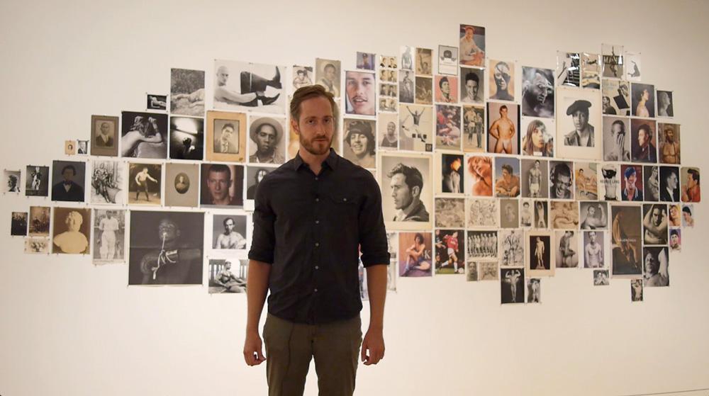 <em>Canadian Art</em> associate editor David Balzer with a project by Vince Aletti at “Fan the Flames: Queer Positions in Photography” at the Art Gallery of Ontario. Photo: Matthew Marie-Rhodes.