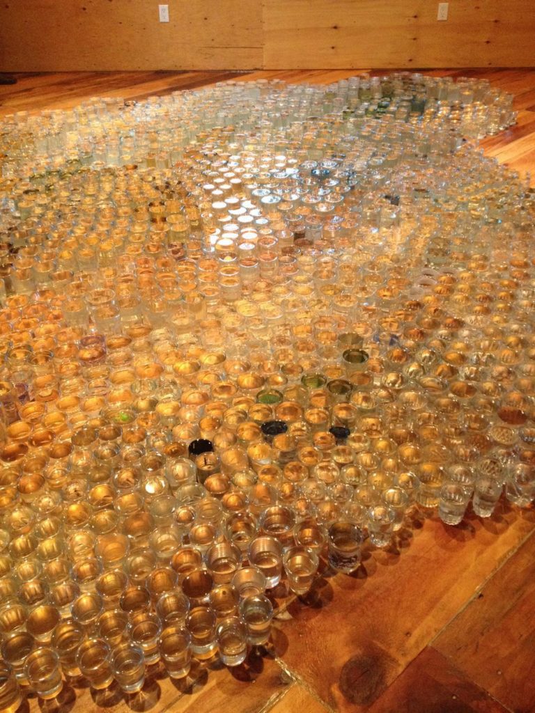 Karen Abel’s installation <em>Riffle Pool Riffle {Mill Creek}</em> involved hundreds of glasses of fluid from a nearby waterway being installed in a barn.  