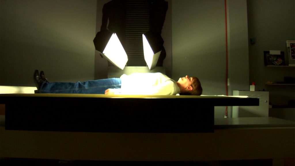 Artist Suzy Lake submits herself to a full-body scan to create an artwork in this still from Annette's Mangaard's new documentary <em>Suzy Lake: Playing with Time</em>. 