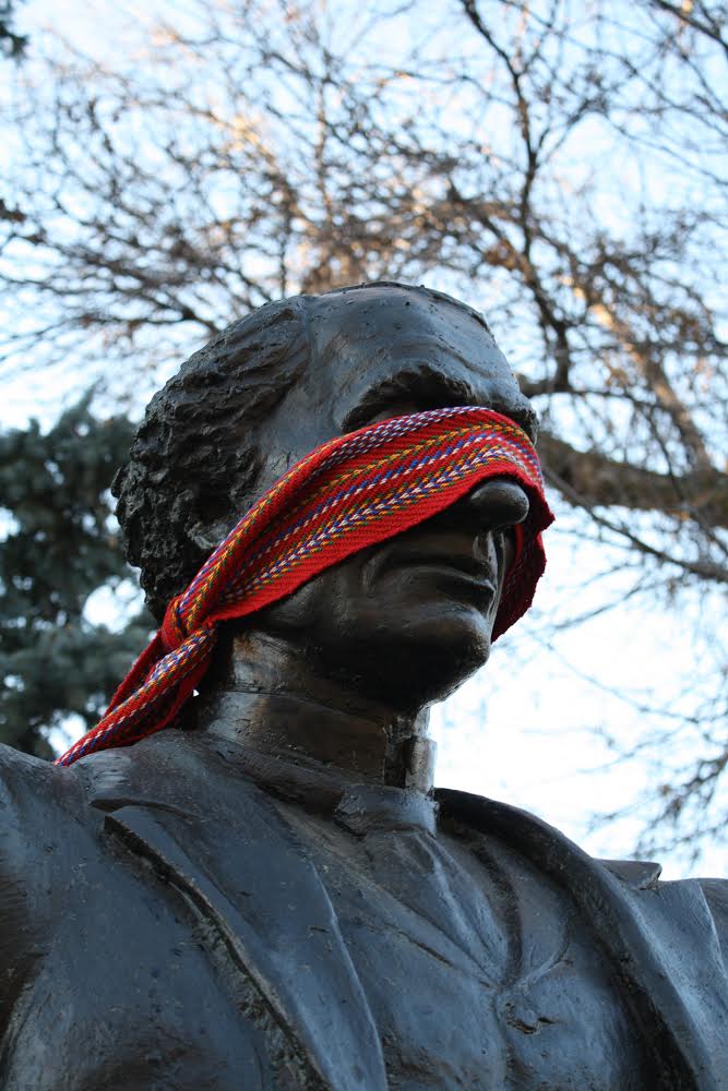 A <em>ceinture fléchée</em> wrapped around the head of the John A. Macdonald statue in Regina's Victoria Park, where Metis artist David Garneau will perform as Louis Riel on November 16.