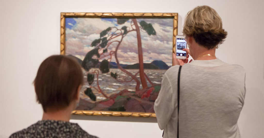 Visitors at the Tom Thomson art gallery with Thomson's <em>The West wind</em> (1917). Image via Facebook.