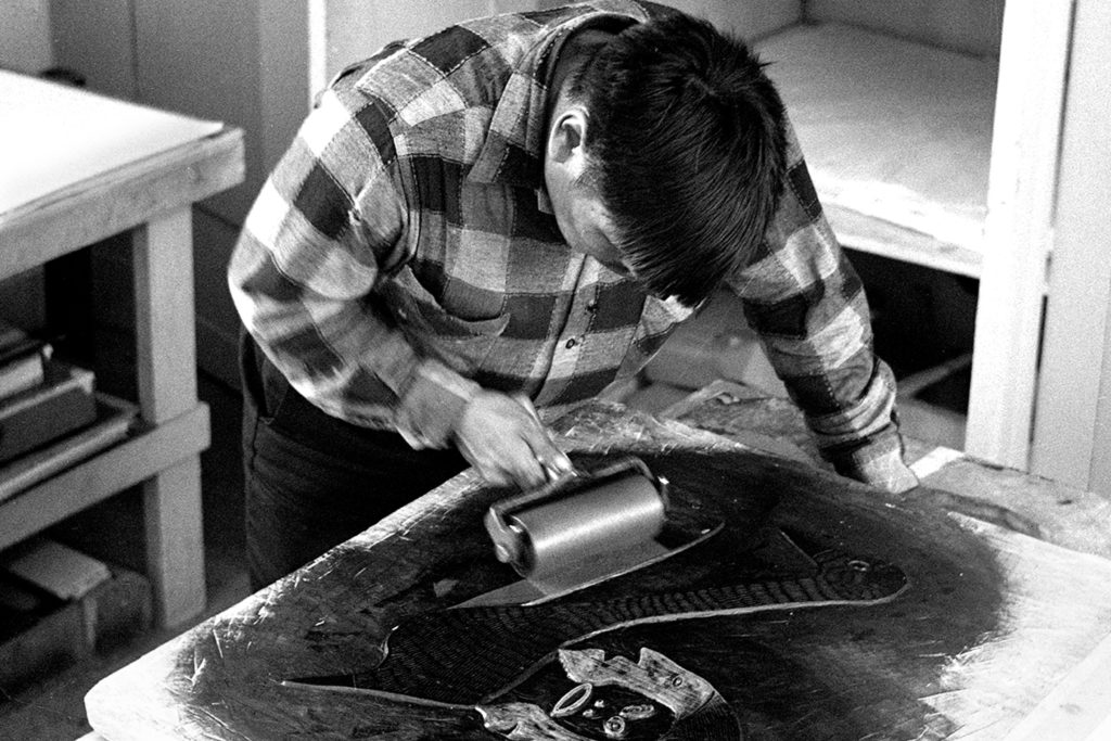 Eegevudluk Pootoogook (1931-1999) inking printstone at the West Baffin Eskimo Co-operative printshop, 1968. Photo: Norman Hallendy (born 1932). Courtesy The Ilagiit Collection: Early Images of Cape Dorset Artists, 1968. Gift of Norman E. Hallendy, 2007. McMichael Canadian Art Collection Archives. 