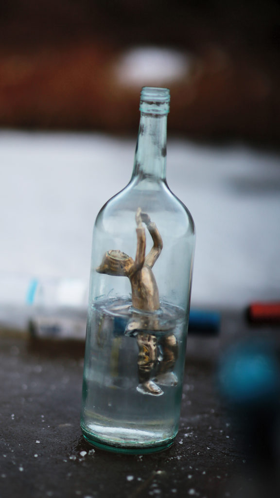 Jesse Tungilik, <em>Bottled</em>, 2018. Bronze-cast figure, clear polyester resin and bottle. Courtesy the artist.