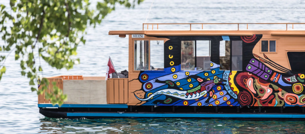 Elder Duke Redbird, <em>Wigwam Chi-Chemung (Big House Canoe)</em>, 2019. Installation view of 40-foot pontoon houseboat painted by Phil Cote and Duke Redbird. Courtesy the artist, Elijah Nichols and Myseum of Toronto.