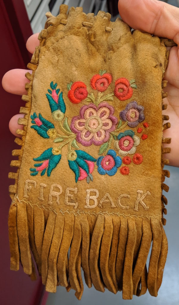 Stitching detail on a hide pouch in collections at the Manitoba Museum that reads “FIRE BACK.”