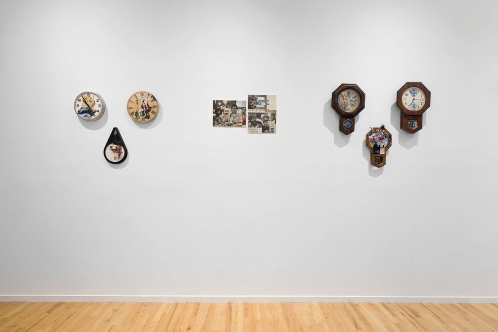 Installation view of a detail of Black Quantum Futurism’s “Experimental Time Order,” 2019. On a white wall we see three wall clocks with collaged faced on either side of three collages.