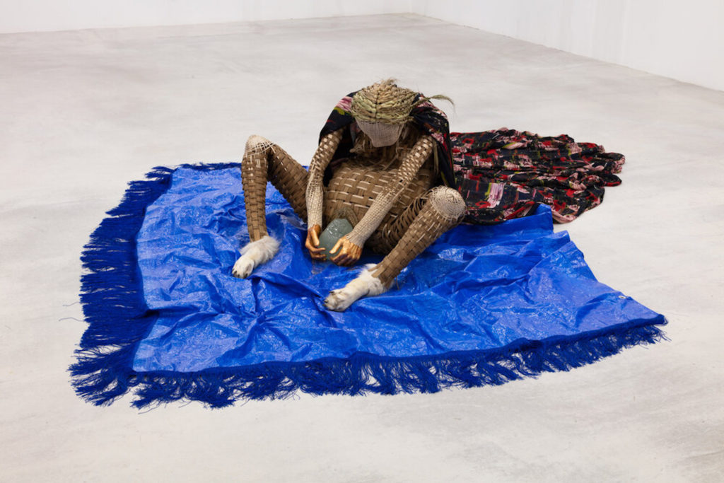 Merritt Johnson, <em>Necessity Channeling Creation</em>, 2020. Woven black ash and reed, sweetgrass, resin, textile, taxidermy wolf’s feet, tarp.