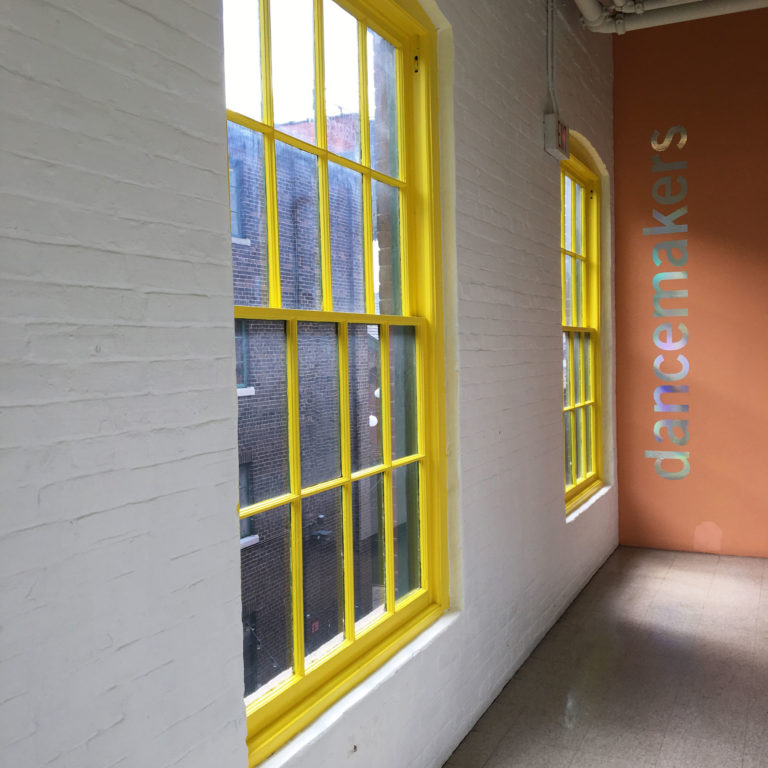 A brightly lit hallway with large windows and logo at end